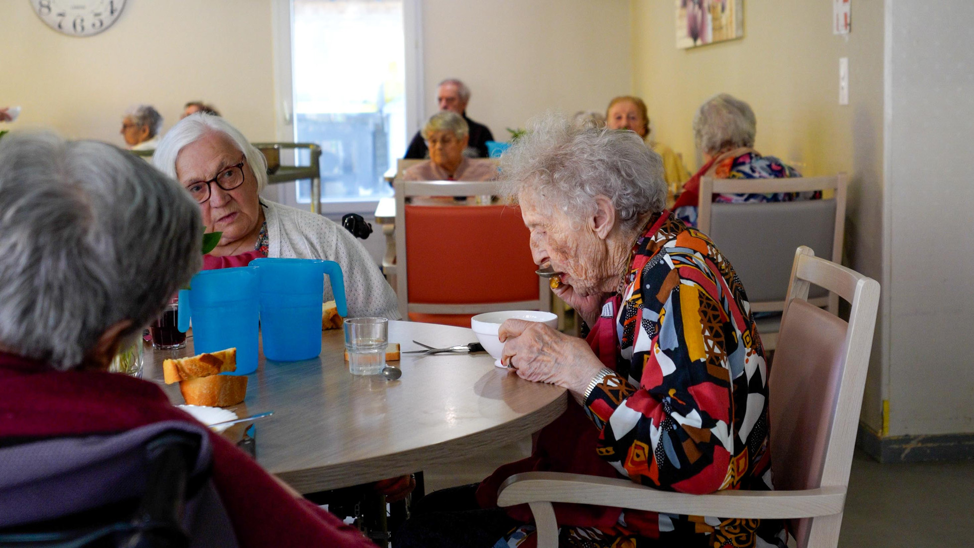 Elderly residents eating together in nursing home dining room