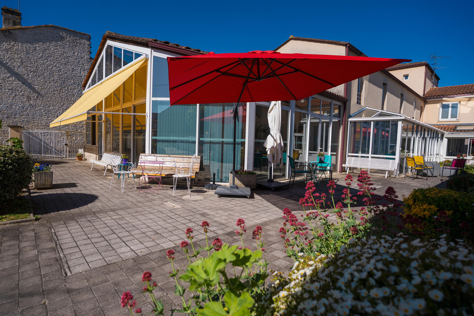 Sunny patio with red umbrella and glass facade