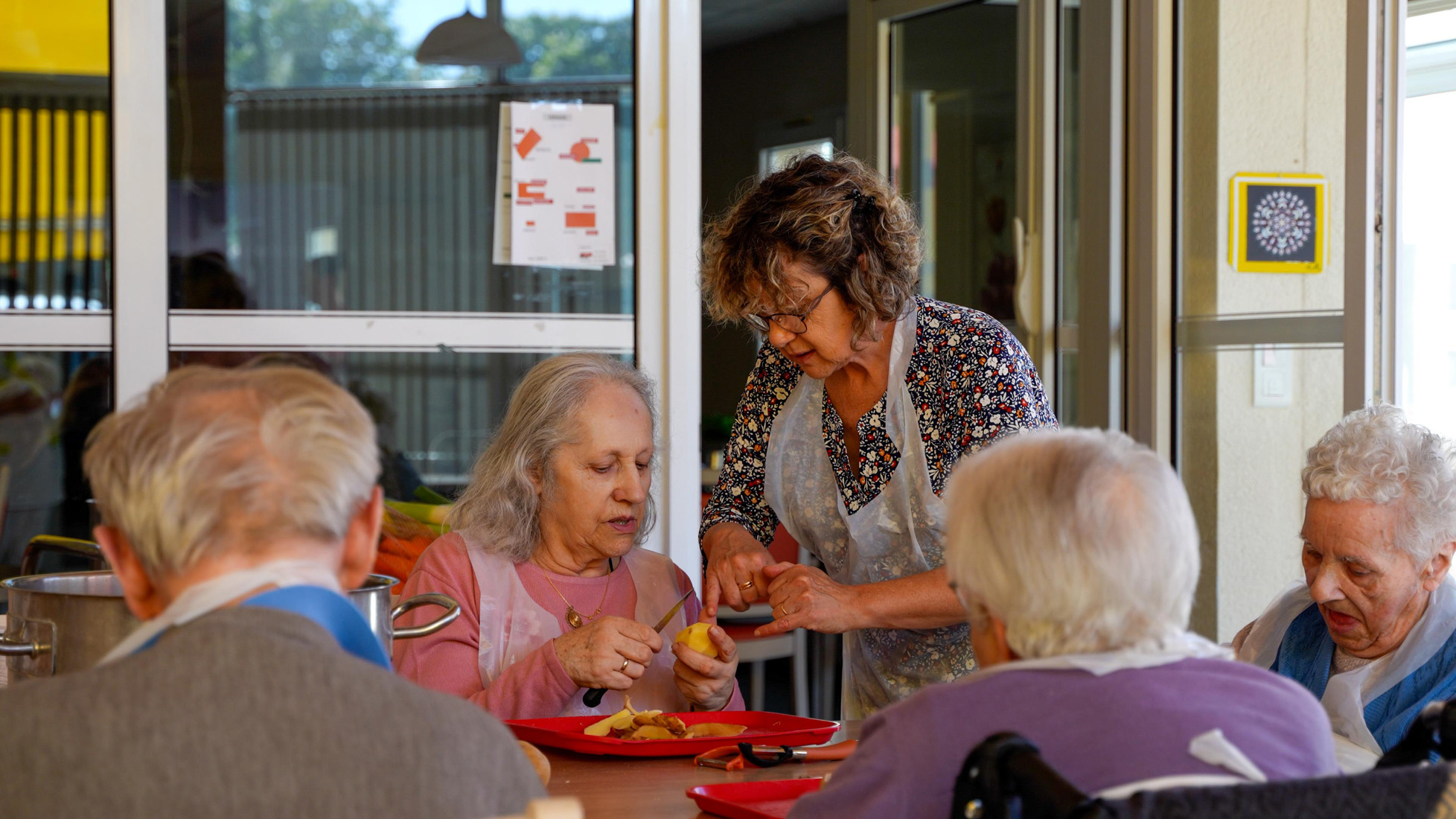 Caregiver assisting seniors with meal preparation indoors