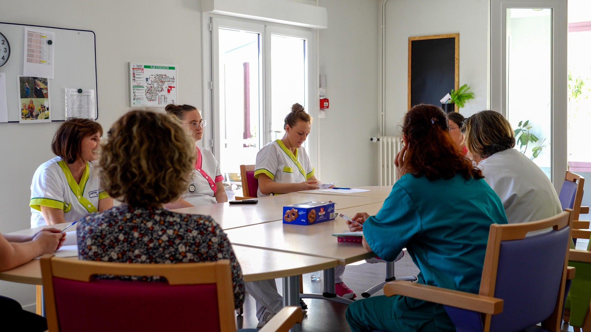 Healthcare staff meeting around table in bright room